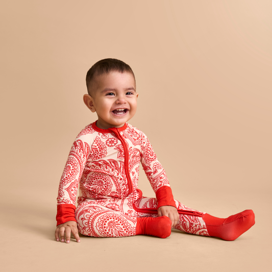 Baby wearing a red and white patterned outfit on a beige background