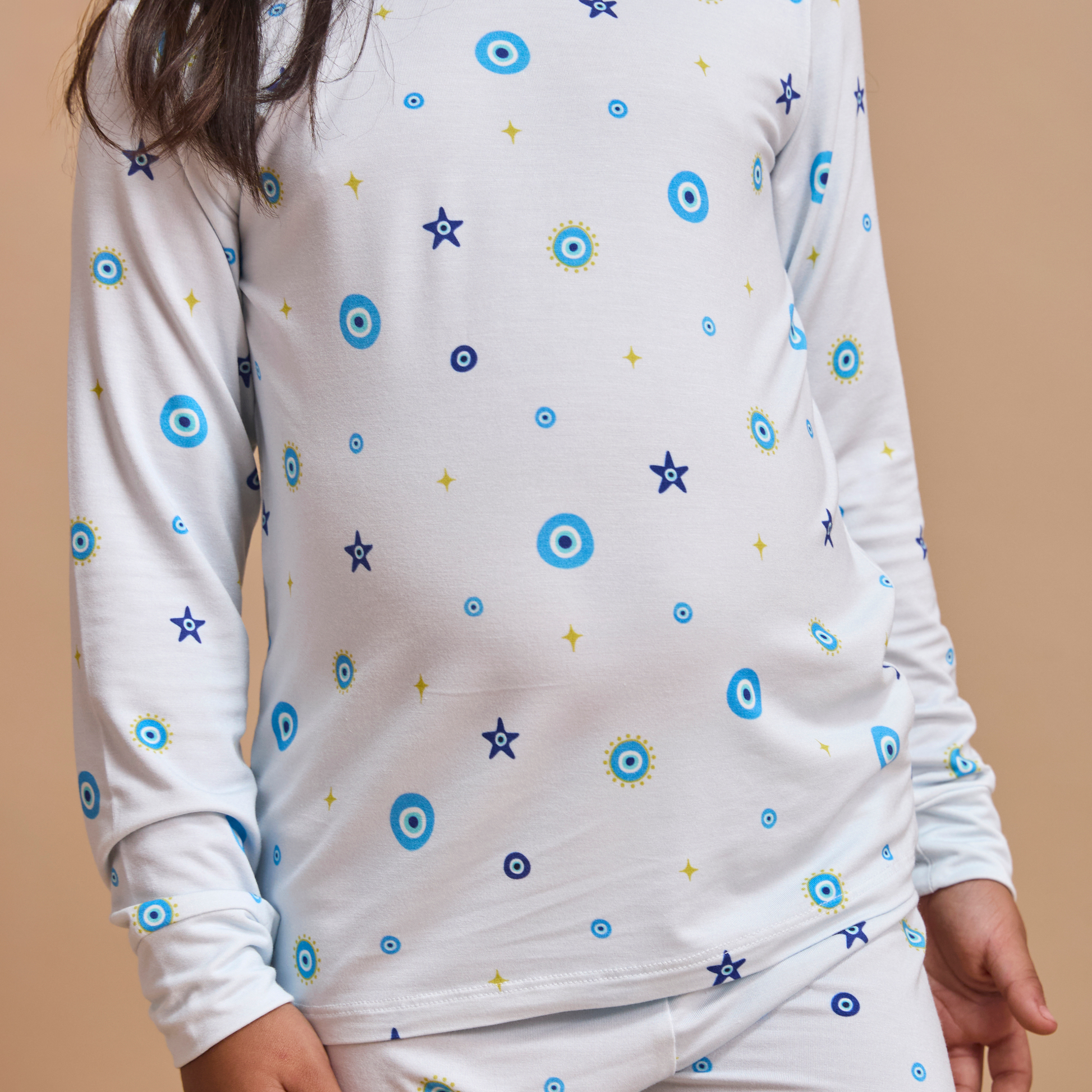 White long-sleeve shirt with blue and yellow star patterns on a beige background