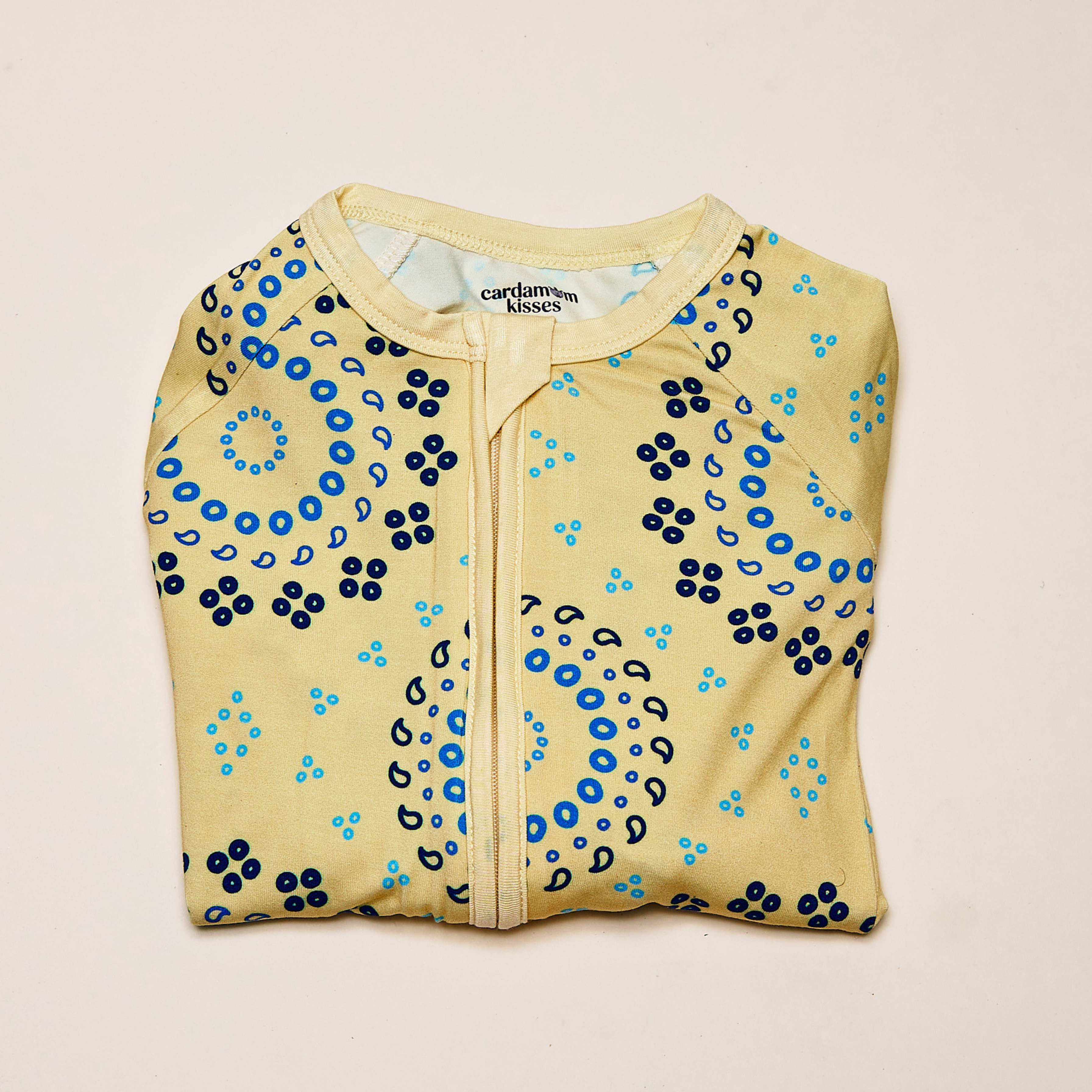 Bandhani Burst baby zippered sleeper with tie-dye inspired print on a beige background