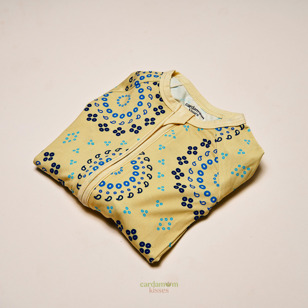 Baby wearing a Bandhani Burst bamboo sleeper on a beige background