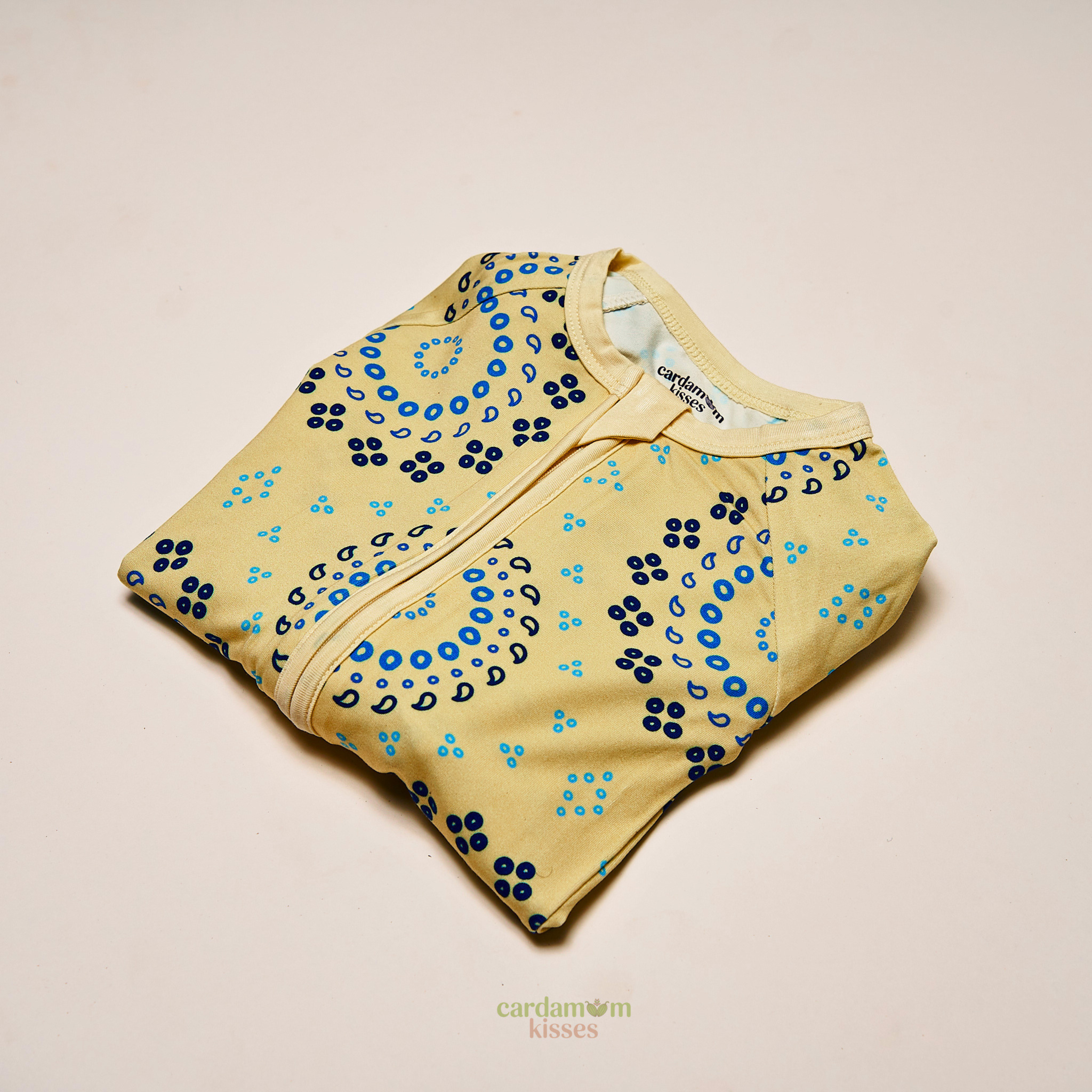 Baby wearing a Bandhani Burst bamboo sleeper on a beige background