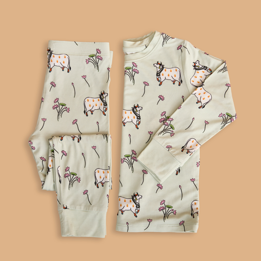 Children's pajama set with cow and flower pattern on a beige background