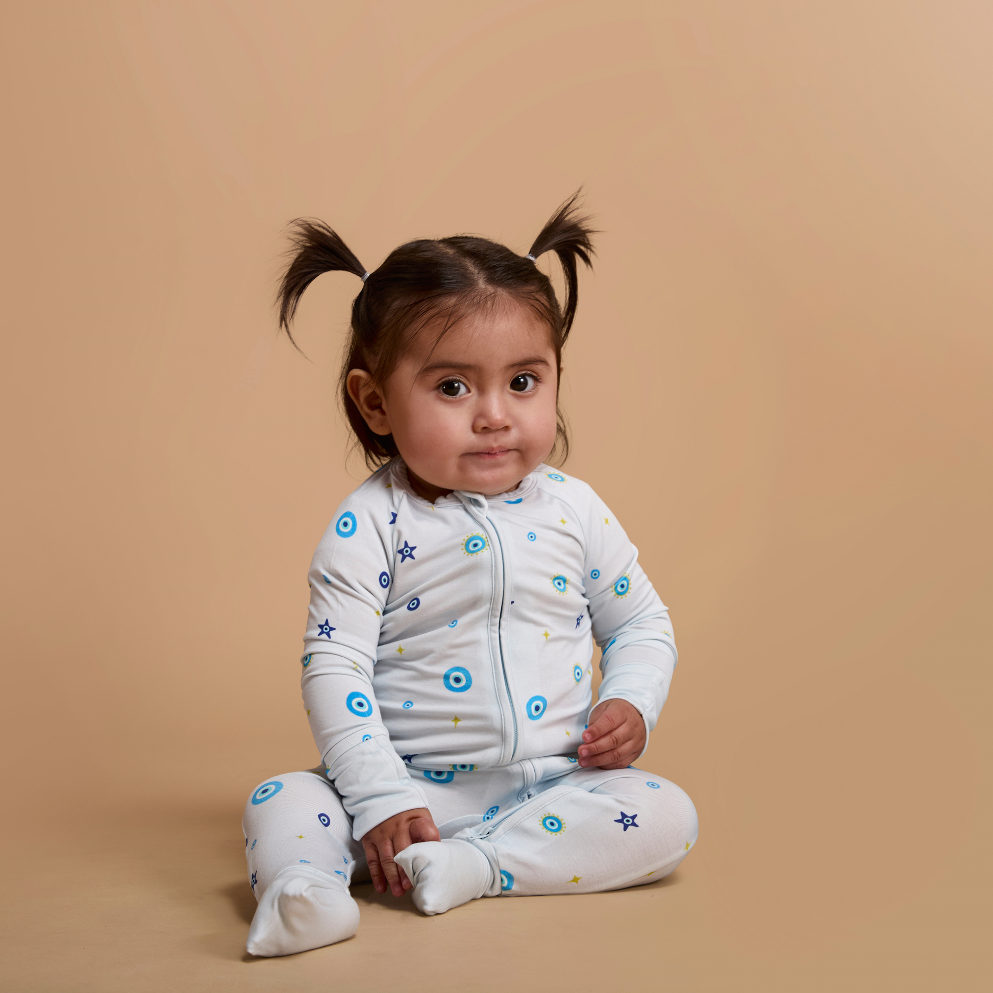 Child wearing a white outfit with blue patterns on a beige background
